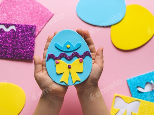 Preview: The hands of a little caucasian girl show the end result of a homemade felt easter egg