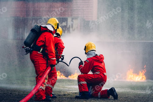 Preview: Fearless Firefighters Battling Blaze with Water and Extinguishers.
