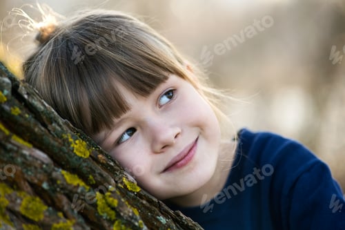 Preview: Portrait of a pretty child girl leaning to a tree trunk in autumn outdoors.