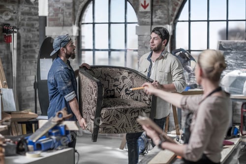 Preview: Manager directing male workers carrying armchair in antique restoration workshop
