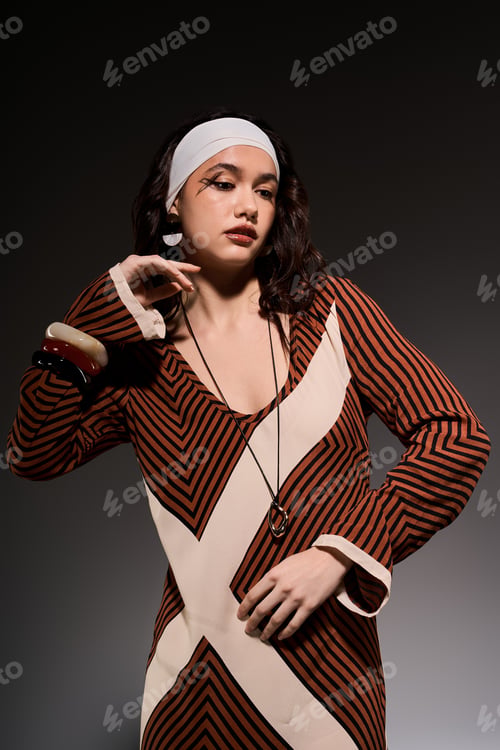 Preview: Stylish young woman showcases bold striped dress in modern studio setting