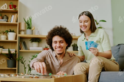 Preview: Cheerful Man And Woman Playing Tabletop Game At Home