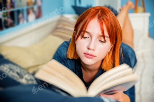 Preview: Pretty red-haired teenage girl reads book in her room