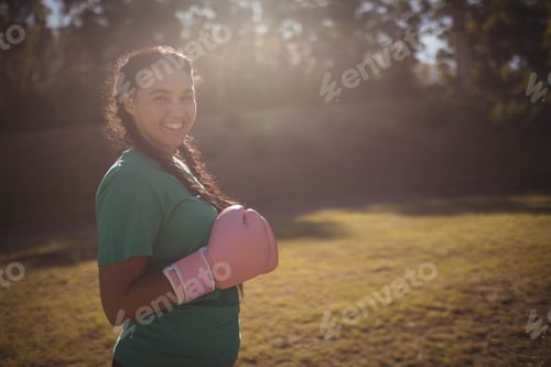 Preview: Pink boxing gloves resting in sunlit grass near tree line with warm light filtering
