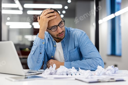Preview: Stressed businessman at office with laptop and paperwork