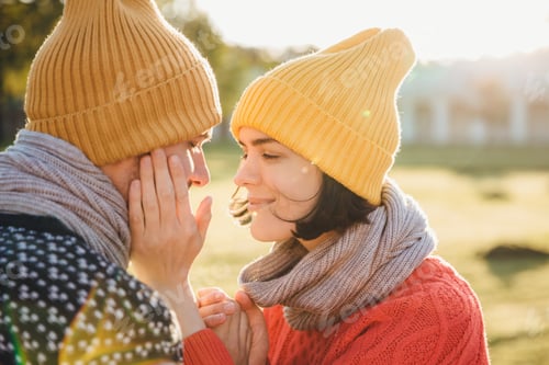 Preview: Woman in warm hat, scarf and sweater, keeps hands on boyfriend’s cheek