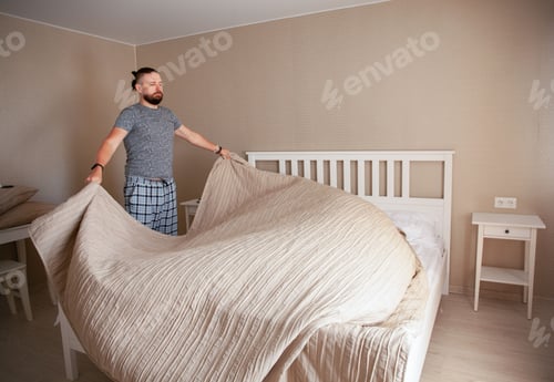 Preview: Man Making Bed in Bright Bedroom at Home