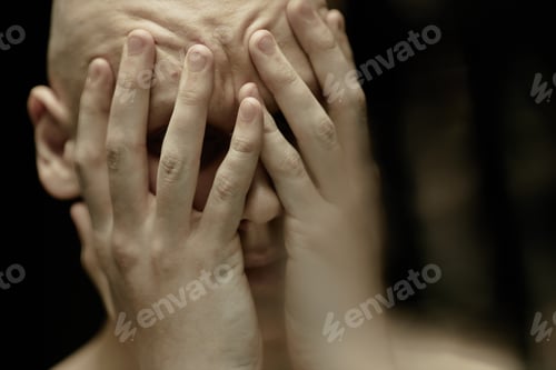 Preview: Bald Man Covering Face with Hands Suffering from Headache in Dark Studio