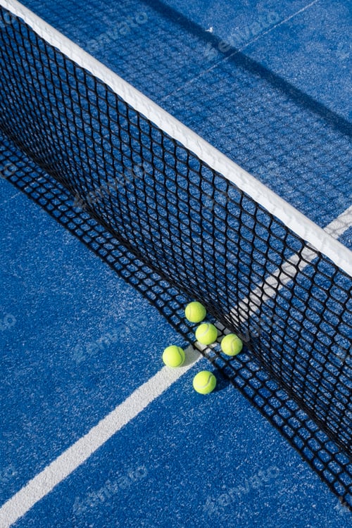 Preview: paddle tennis balls by the net on a blue paddle tennis court