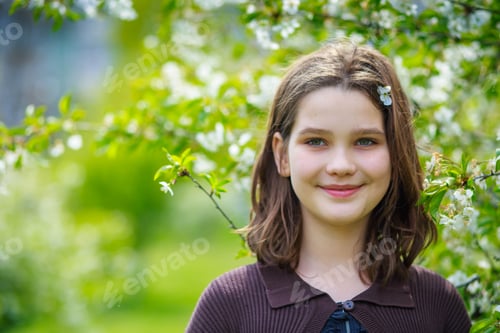 Preview: Beautiful girl among cherry flowers in spring. Portrait of a girl with brown hair and green eyes.