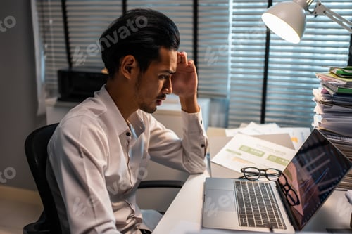 Preview: Frustrated Asian young businessman worker working on table in office.
