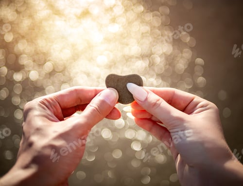 Preview: Hands holding a sandy heart on the beach against the sea waves
