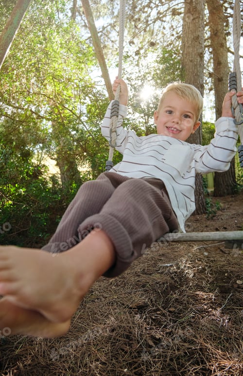 Preview: Cheerful boy on swing in park