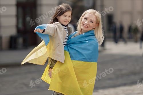 Preview: Mother and her daughter standing with a flag of Ukraine on a street