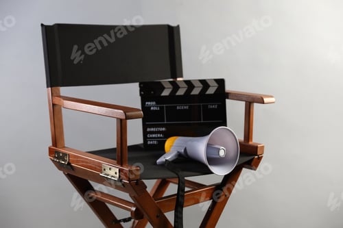 Preview: Director's chair with clapperboard and megaphone on light grey background, closeup