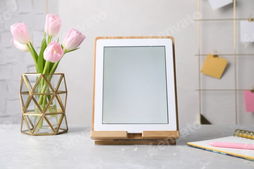 Preview: Modern tablet, stationery and flowers on grey marble table. Space for text