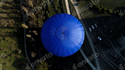 Preview: Aerial view of a blue balloon in the sky over the countryside area, France. Shot. Flying above trees