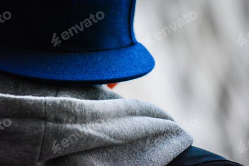 Preview: Closeup shot of someone wearing a gray hoodie and a blue hat