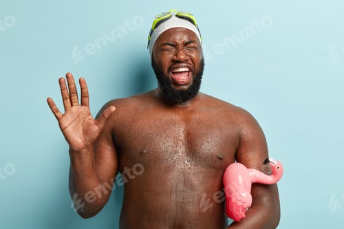 Preview: Strong muscular man wet after swimming in sea, shows palm, closes eyes, asks not spray cold water on