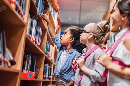Preview: beautiful little schoolgirls looking for books in library