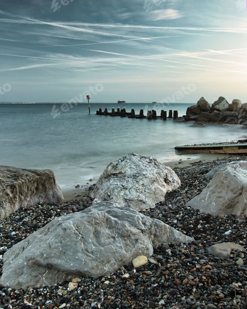 Preview: Picturesque pathway of rocky terrain winds along the shoreline of a tranquil body of water