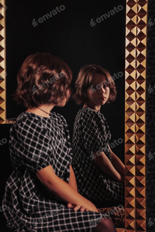 Preview: Portrait of pretty cute teenager girl in an elegant dress at mirror