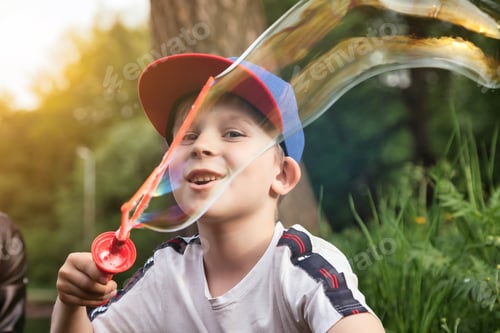 Preview: Son with mom having fun on green lawn with soap bubbles in summer public park, together in sunny day