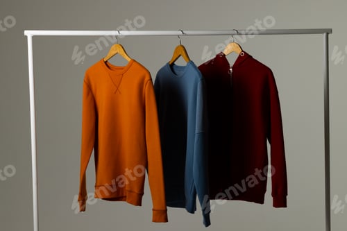 Preview: Coloured sweatshirts displayed on clothing rail and copy space on white background