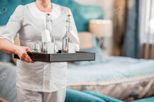 Preview: Chambermaid holding a tray with water in the hotel room