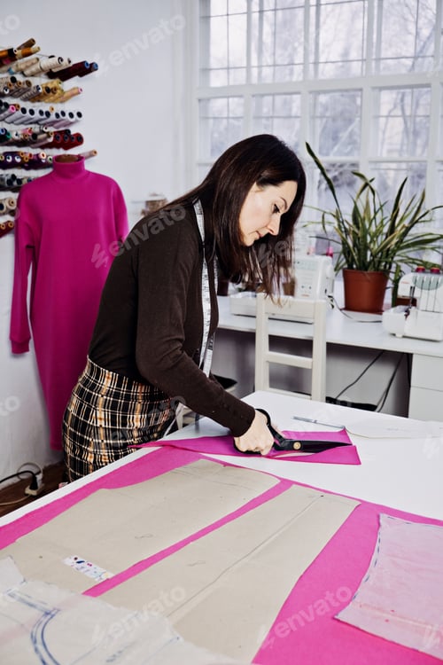 Preview: Female fashion designer tailor making sewing patterns at workplace in sewing studio.