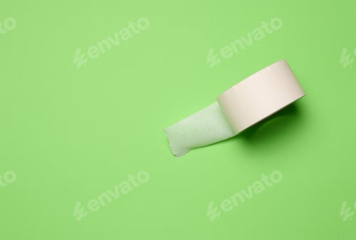 Preview: Roll of paper masking tape on green background, top view