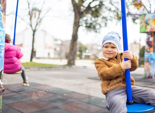 Preview: A boy on a playground in an autumn park rides on a swing in cloudy weather