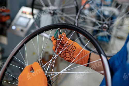 Preview: Worker in gloves installs bicycle spokes, factory