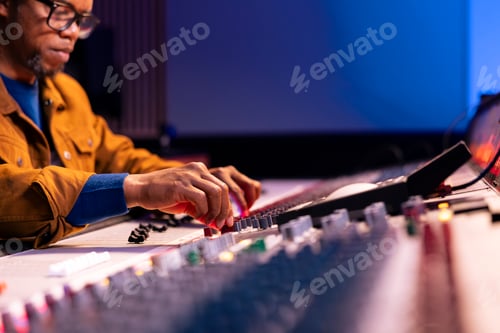 Preview: Man Adjusting Levels on Audio Mixing Board