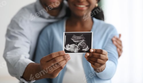 Preview: Closeup of baby sonogram in black couple hands