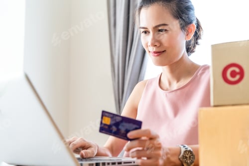 Preview: Asian young woman sit in chair, look at laptop for shopping online from home.
