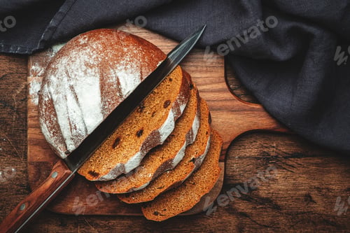Preview: Sourdough rye bread with raisins, pieces on wooden cutting board, bread knife