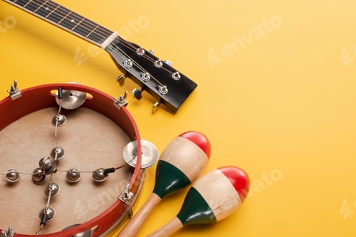 Preview: Tambourine near colorful wooden maracas and acoustic guitar on yellow background