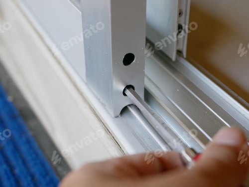 Preview: Close up of a screwdriver in a man's hand adjusting sliding glass door rollers