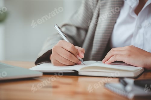 Preview: Female student taking notes from a book computer and smartphone at the table An Asian woman sits at