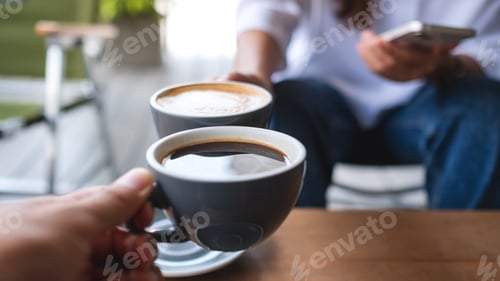 Preview: Closeup image of a couple people clinking coffee cups together in cafe