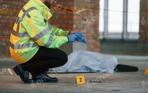 Preview: Male detective is collecting evidence in a crime scene near dead body on the construction site
