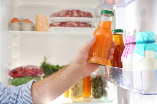 Preview: Man taking bottle with juice out of refrigerator in kitchen, closeup
