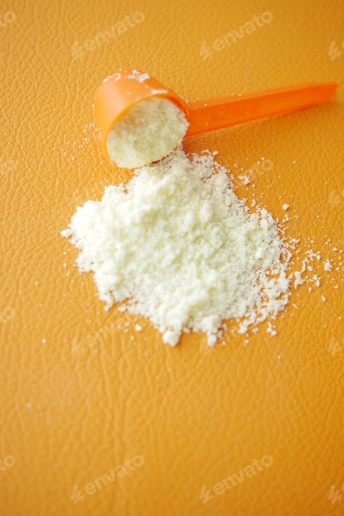 Preview: Close up of baby milk powder and spoon orange background