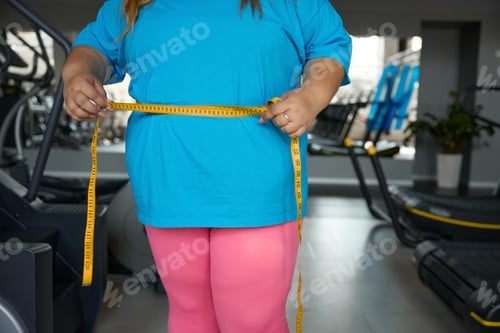 Preview: Closeup waistline of overweight woman wrapped in measuring tape