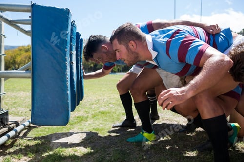 Preview: Side view of rugby players crouching at field