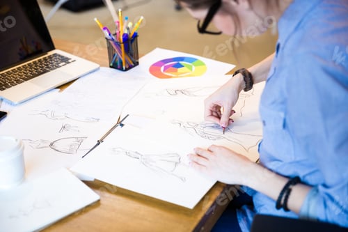 Preview: Creative woman fashion designer in glasses sitting and drawing sketches
