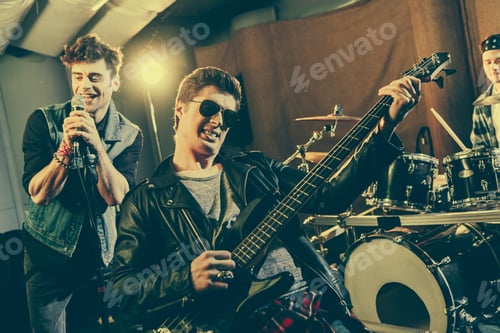 Preview: selective focus of stylish guitarist in sunglasses playing electric guitar near rock band