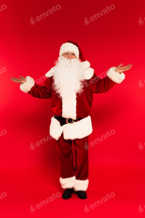 Preview: Father christmas in costume pointing with hands on red background