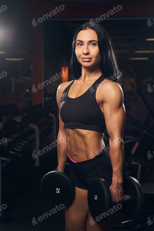 Preview: Well-shaped female athlete posing wiht a pair of dumbbells
